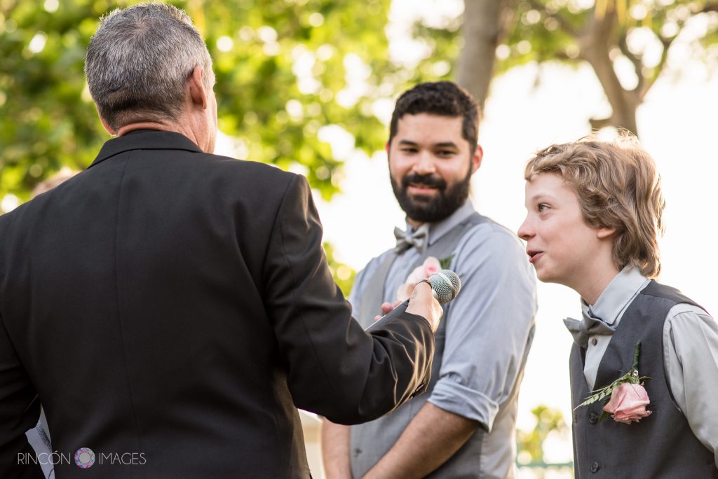 The young son of the groom speaking into the microphone during the wedding ceremony while his older brother looks on.