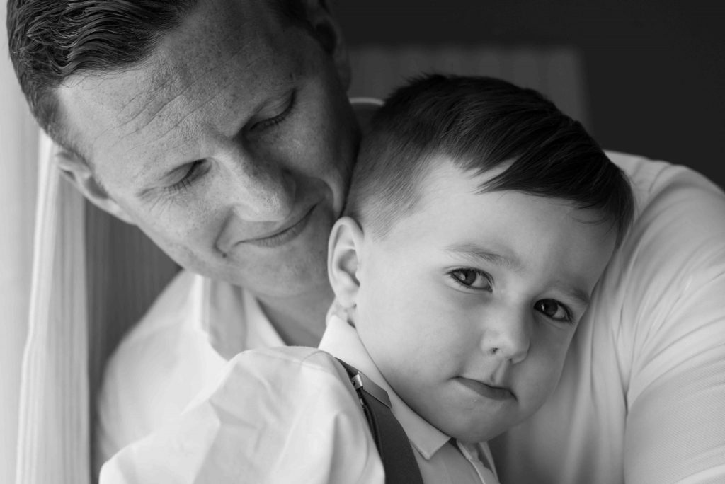 Groom and his son hugging on wedding day.