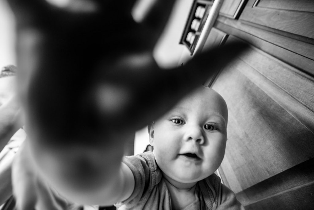 Baby holding his hand out towards the camera.