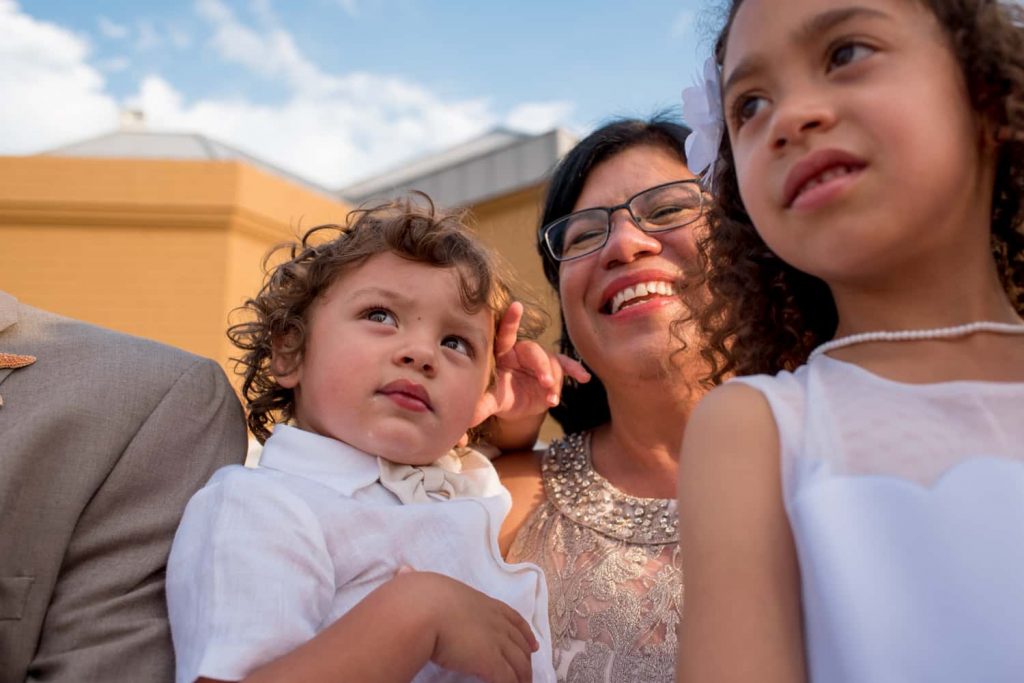 Ring bearer and flower girl sitting on the grandmothers lap during a wedding reception