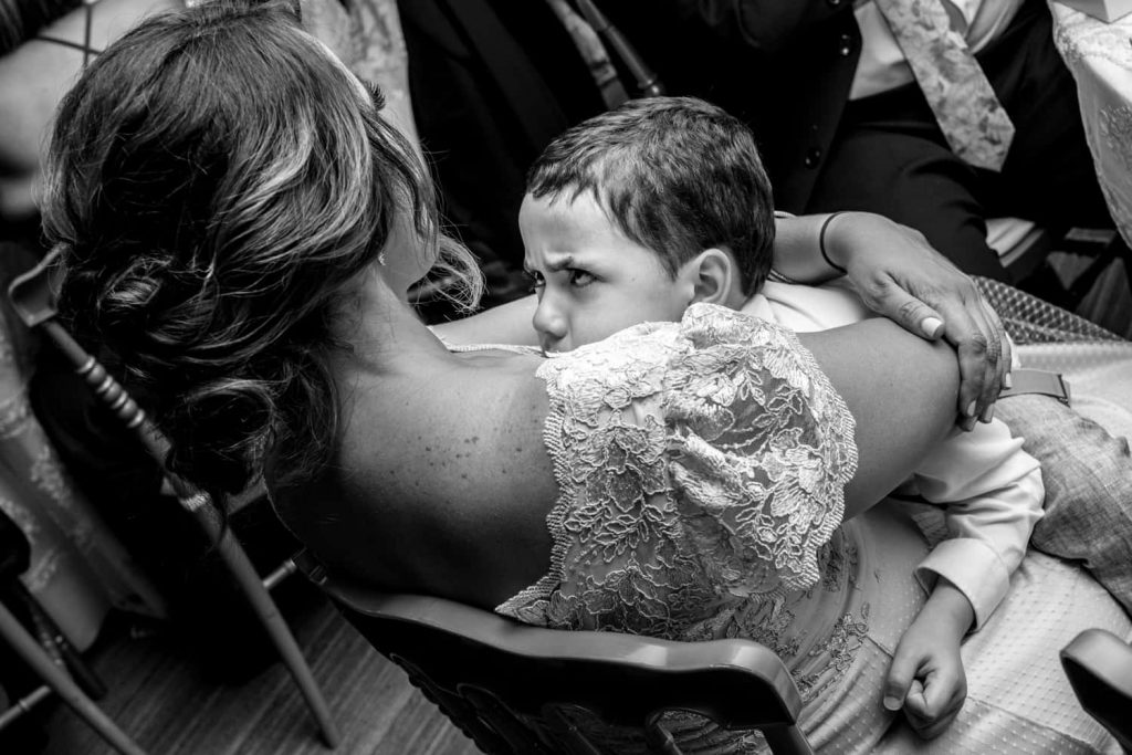 Grumpy young boy sitting on his mothers lap