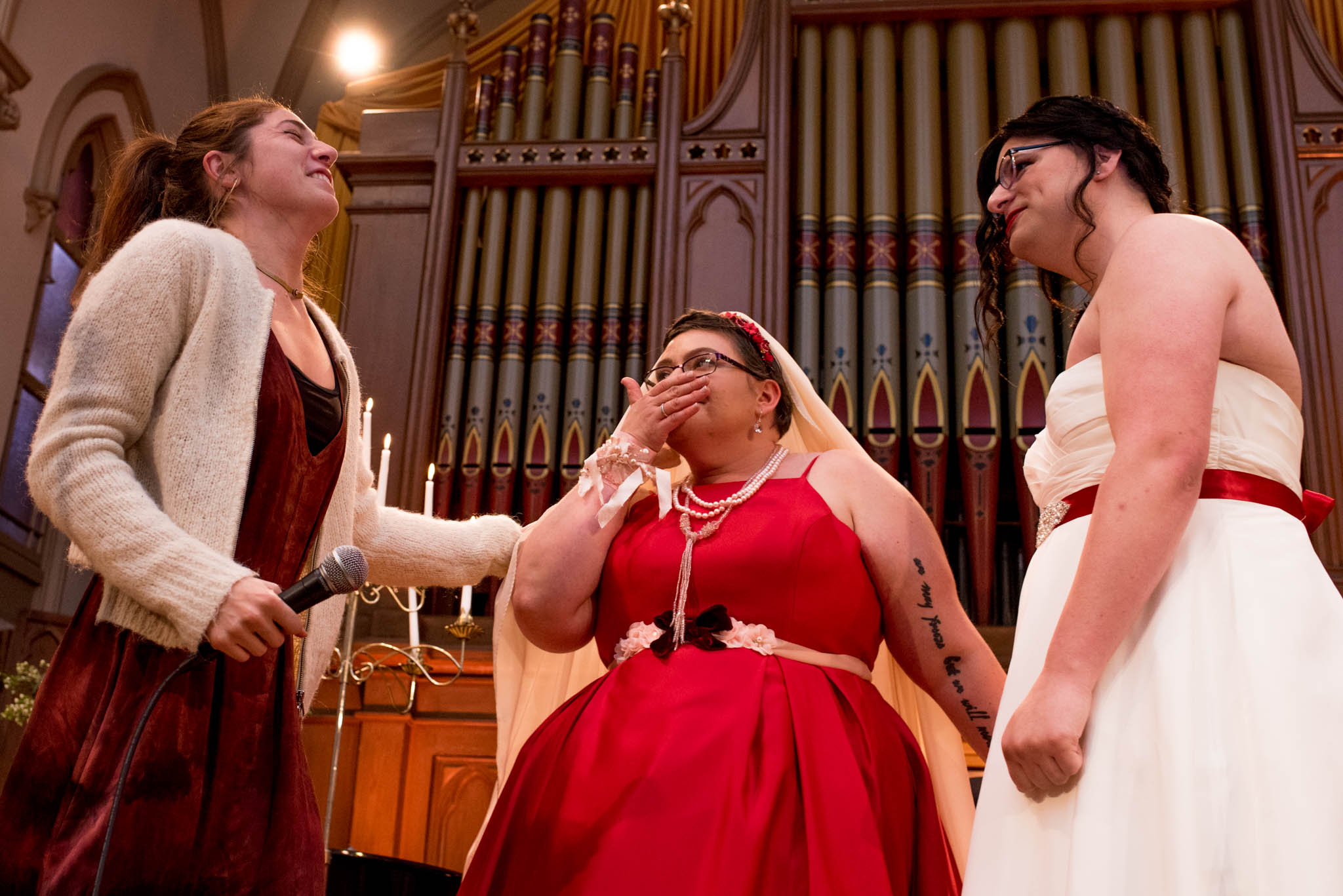 Brides laughing during wedding ceremony in front of old organ