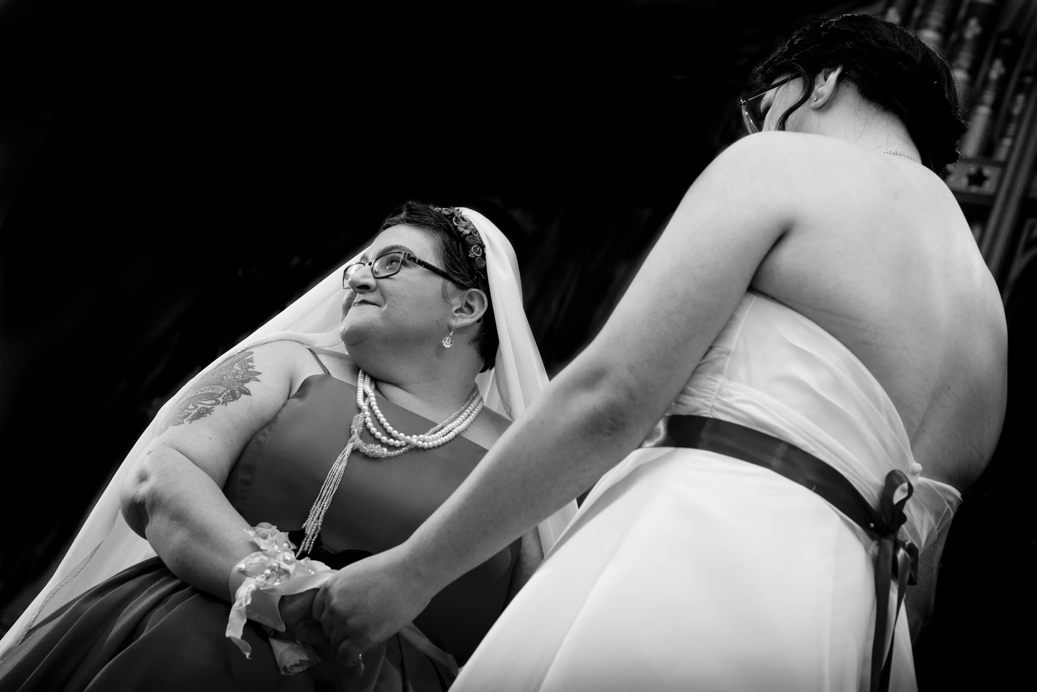 Photograph of two brides holding hands during ceremony