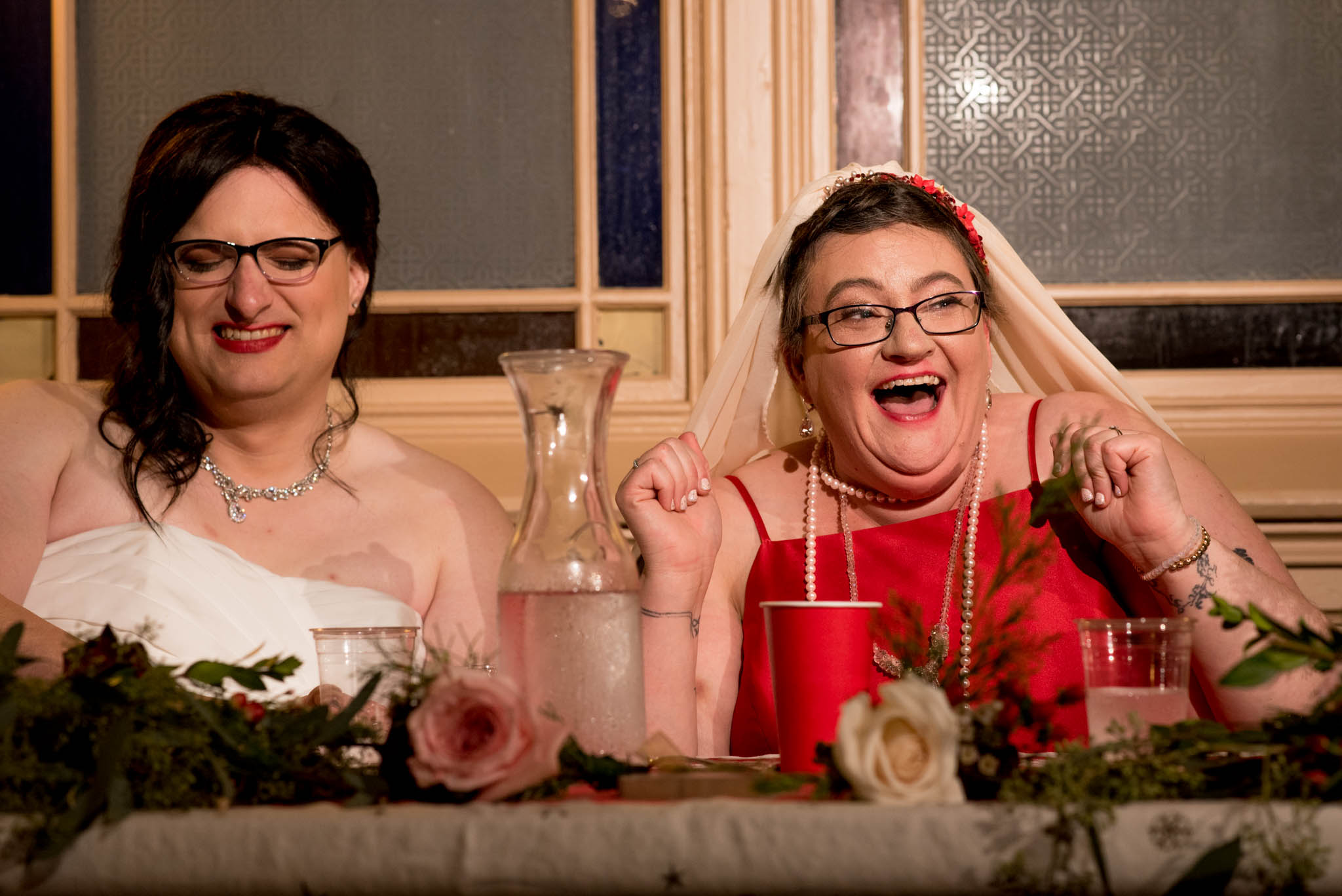 Brides smiling and reacting to wedding toasts