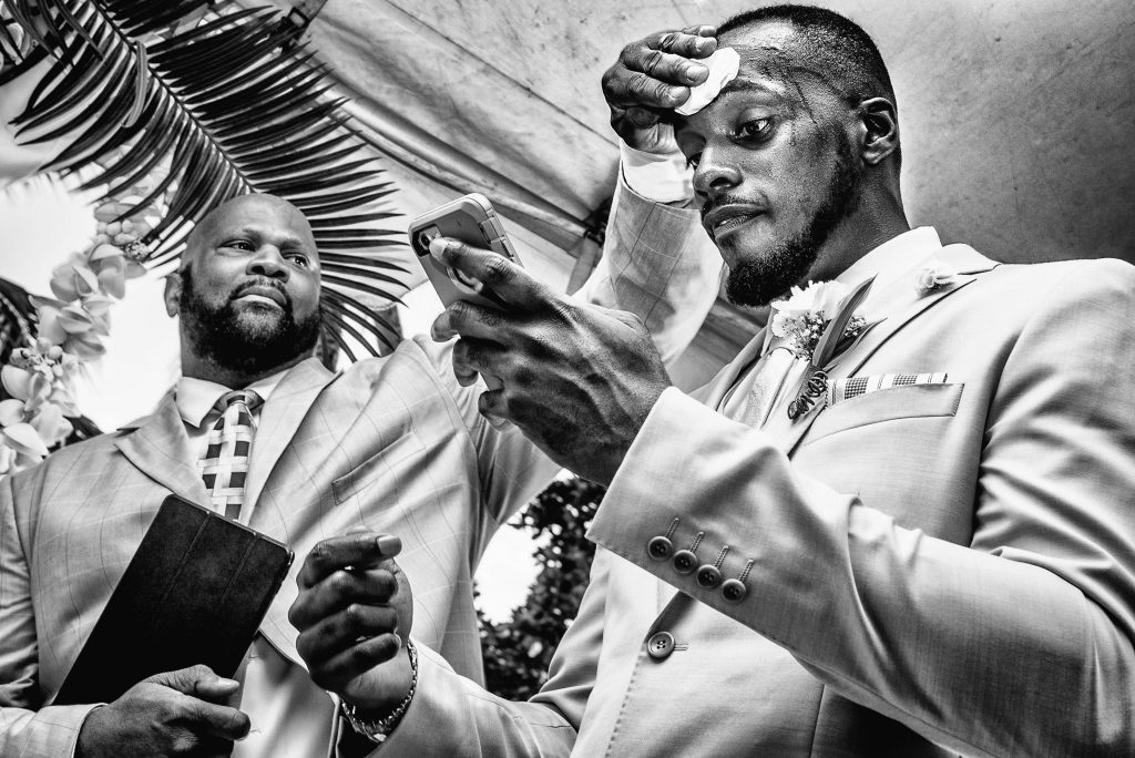 Pastor wiping sweat off of grooms forehead during wedding ceremony
