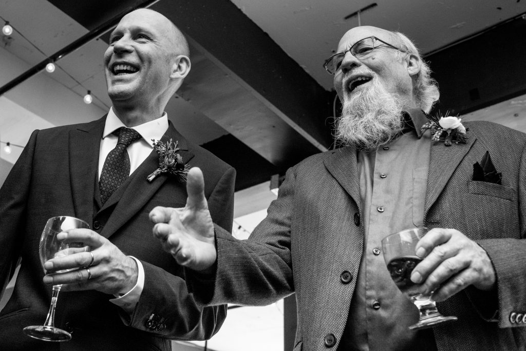 The groom and his father laughing and smiling on wedding day.