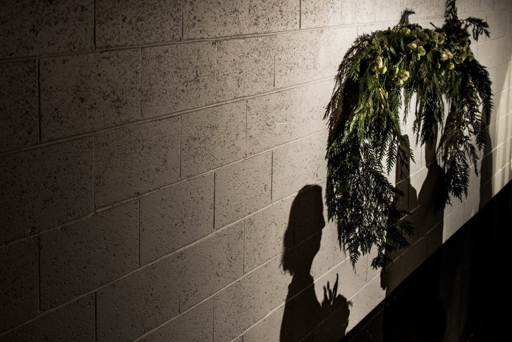 Shadow of the bride on the wall next to her wedding arch.