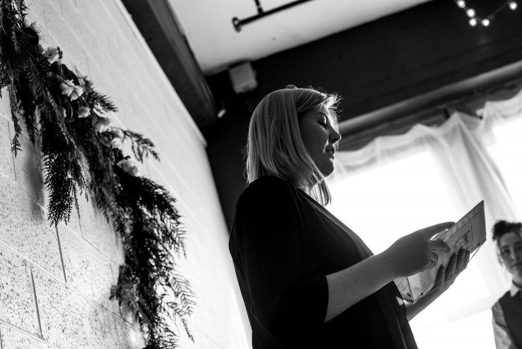 Black and white photograph of officiant reading wedding ceremony.