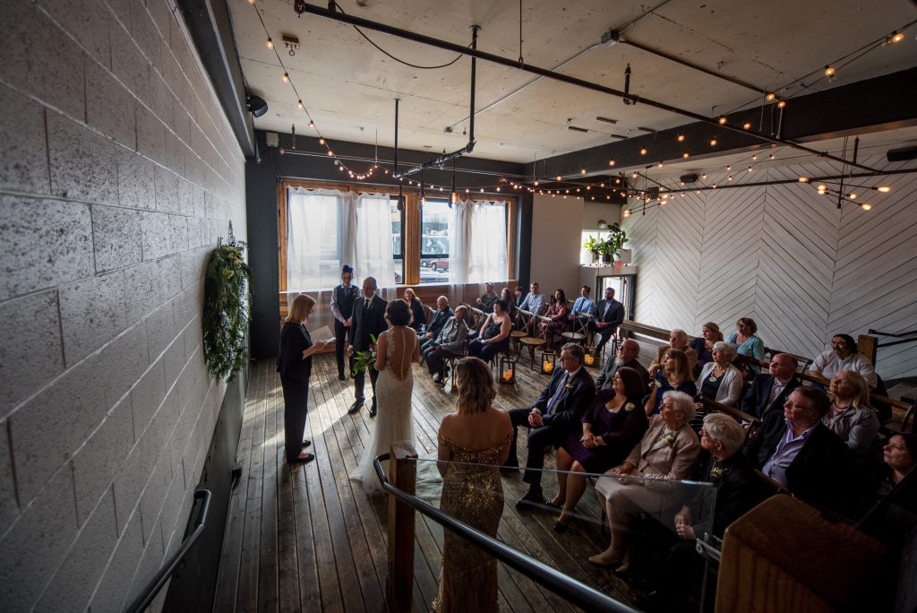 Union pine wedding ceremony filled with people and natural light from the windows.