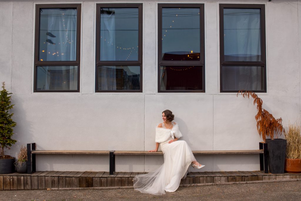Bride sitting in front of building with four windows.