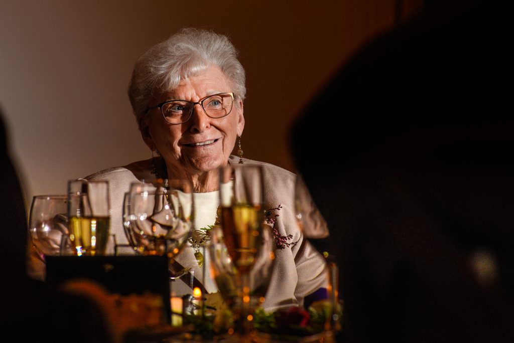 Grandmother smiling siting at a table with wine glasses