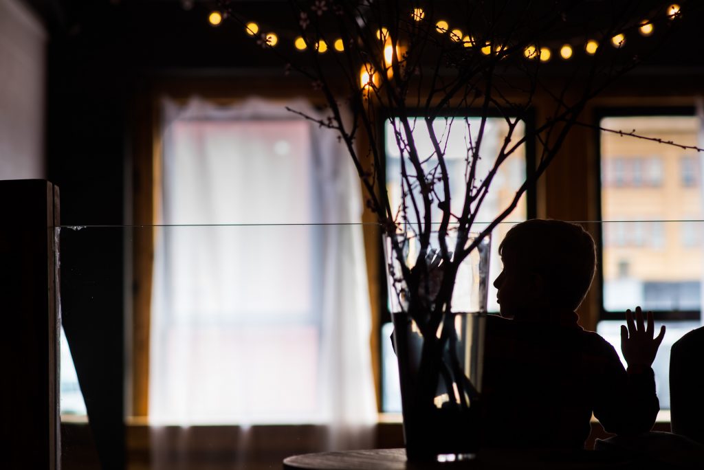 Silhouette of a child playing by flowers during a wedding reception.