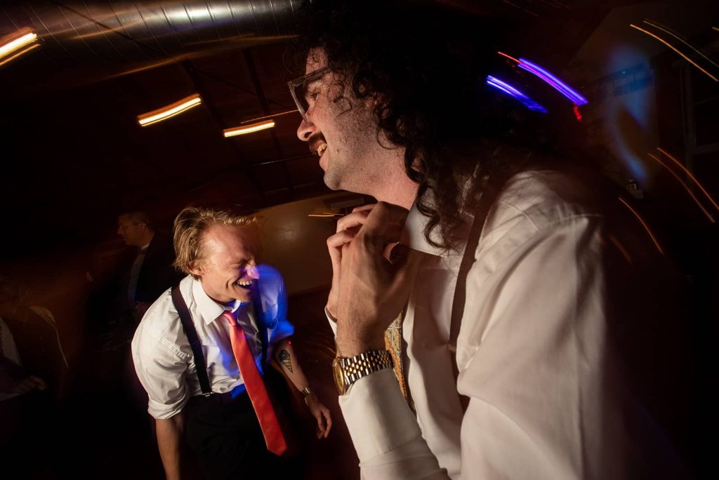 Stylized photo of two groomsmen having a great time at the reception in The Loft at The Red Building in Astoria, Oregon.