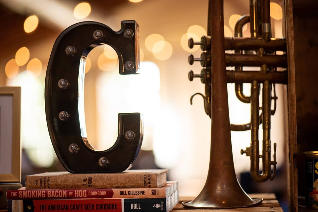 Picture of letter C on top of stacked three vintage books with a saxophone as reception decor for a wedding.