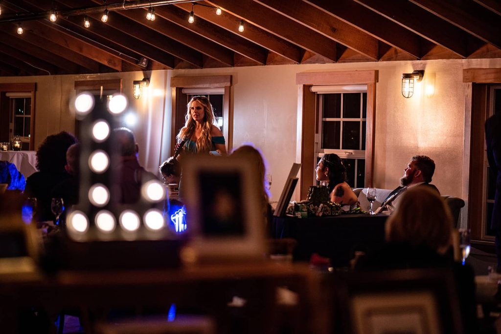 A bridal party member is delivering a speech at the reception, standing beside the bride and groom