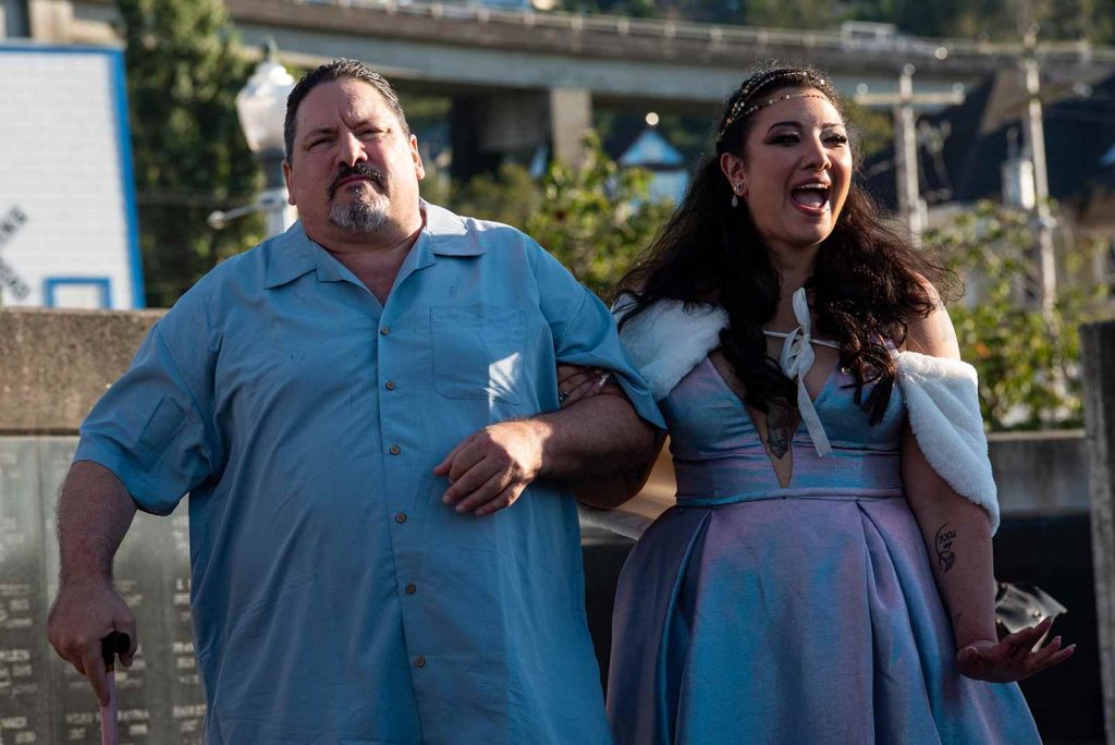 The beautiful bride walks with her father holding his hand at the ceremony in The Maritime Memorial Park.