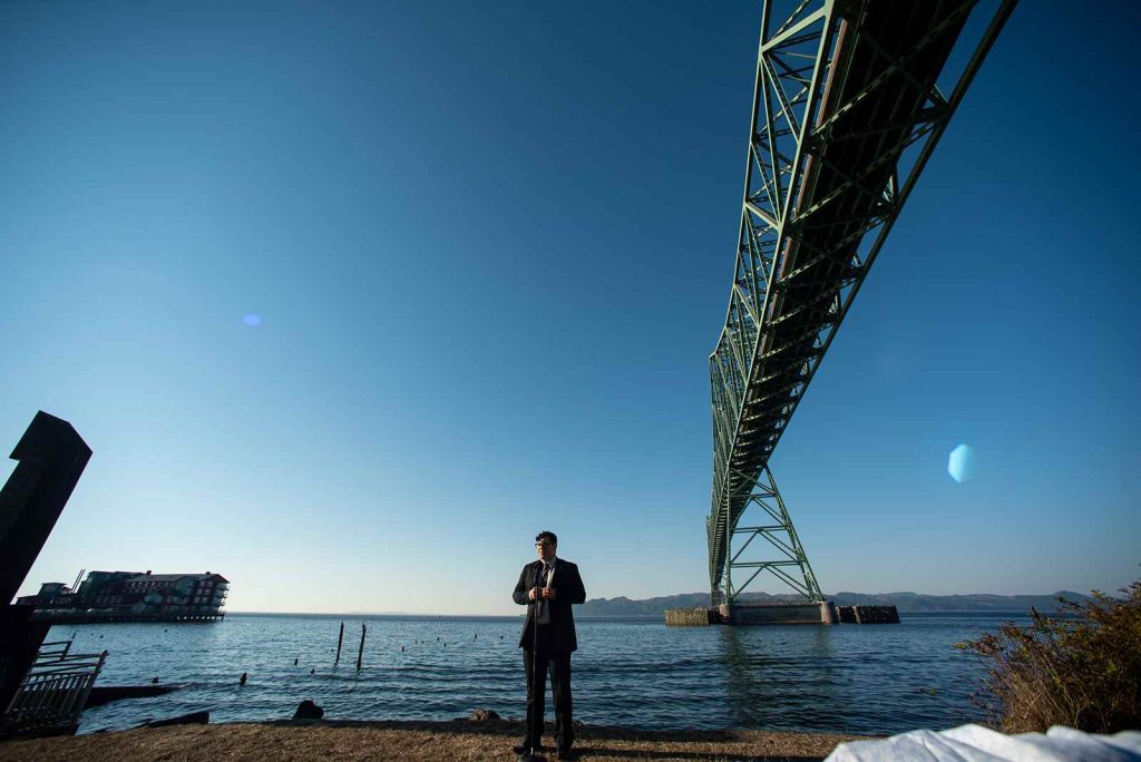 Officiant standing alone by the waters at the ceremony in The Maritime Memorial Park waiting for the wedding to begin.