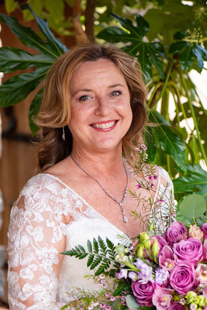 a woman in a white dress holding a bouquet of flowers.