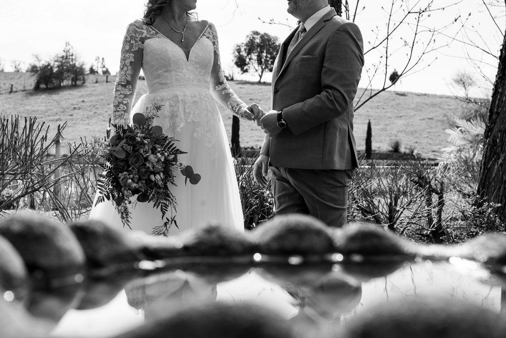 a man and a woman standing next to each other holding hands in front of a fountain