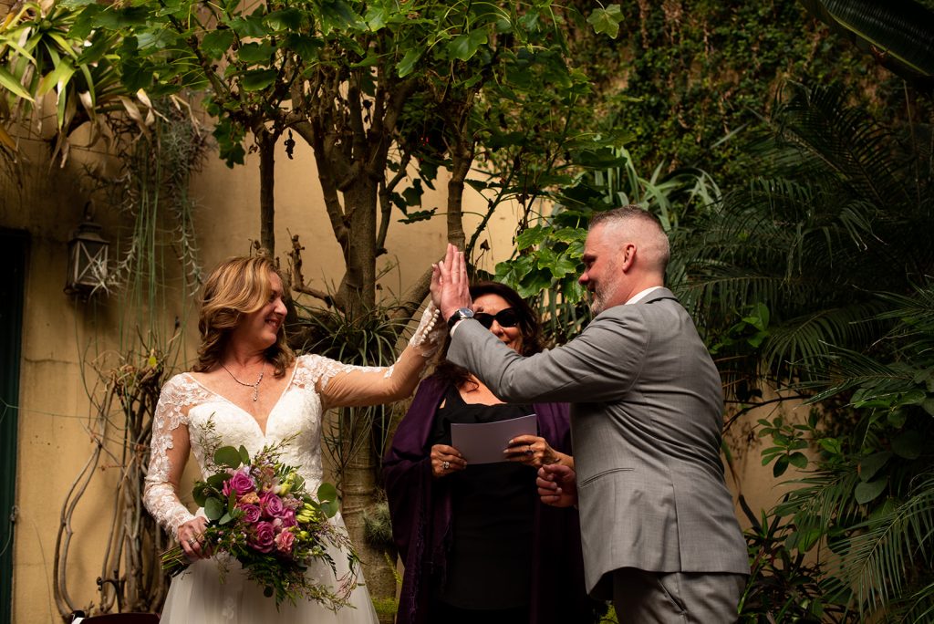a bride and groom holding their hands up to each other.