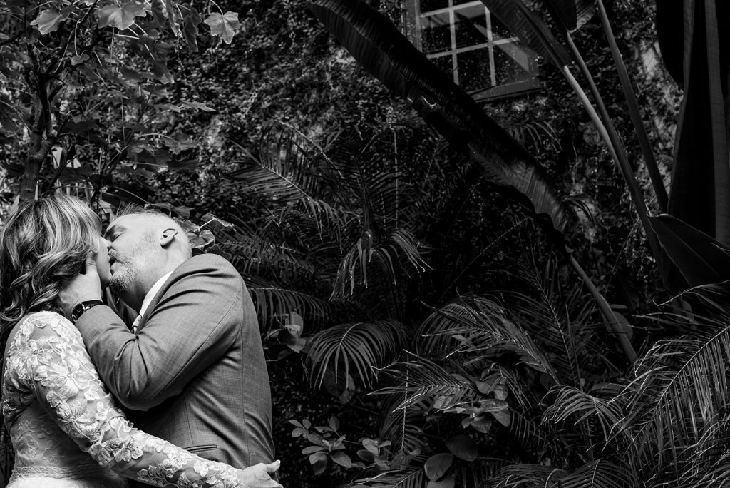 a bride and groom kissing in front of trees.