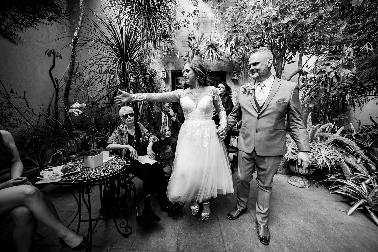a bride and groom walking through a garden.