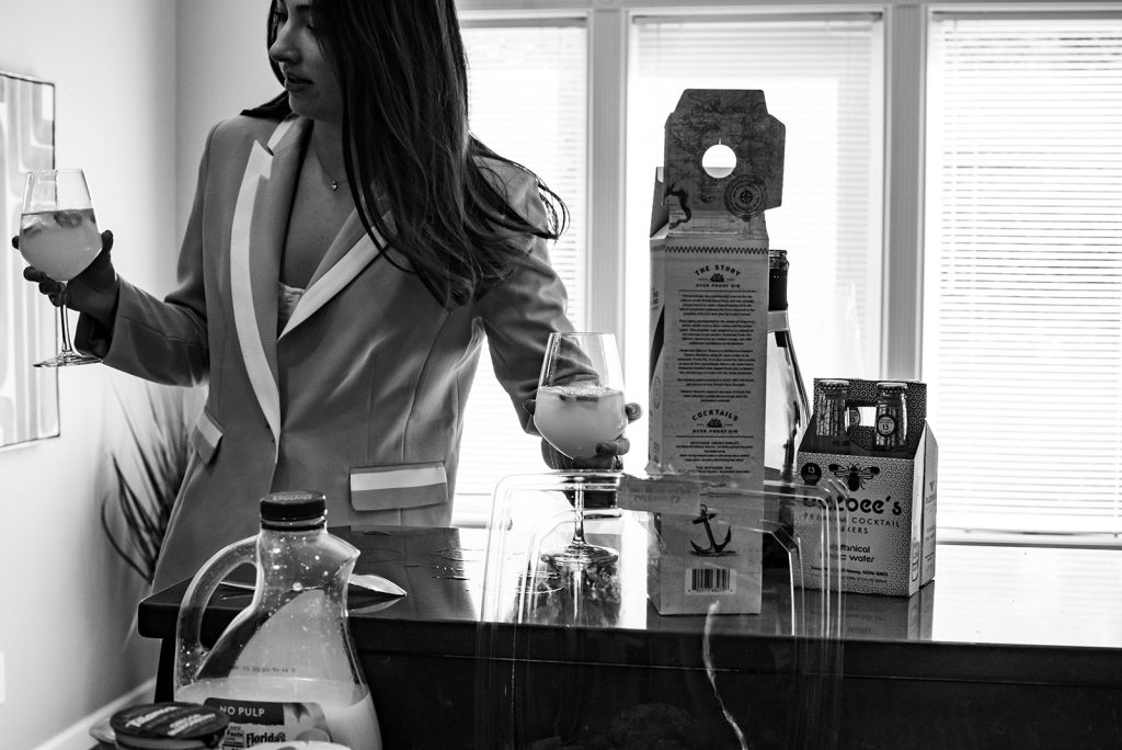 a woman standing next to a counter holding a wine glass.