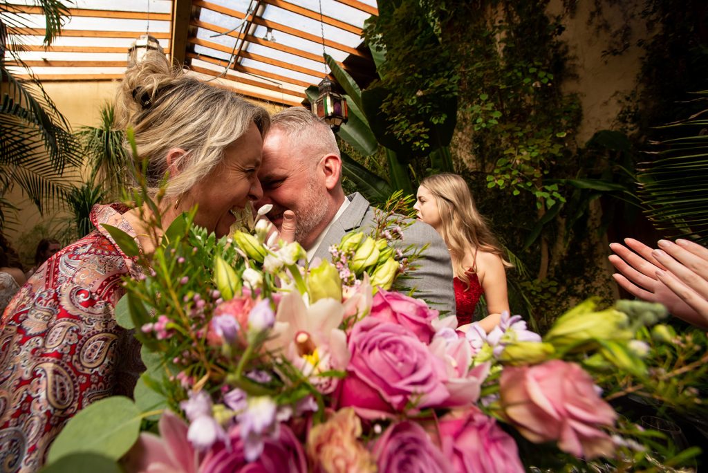 a couple of people that are hugging each other with a bouquet of wedding flowers