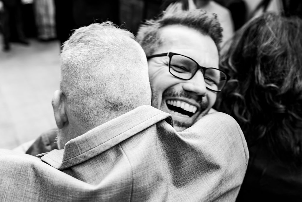 a man is hugging another man at a wedding in Oregon