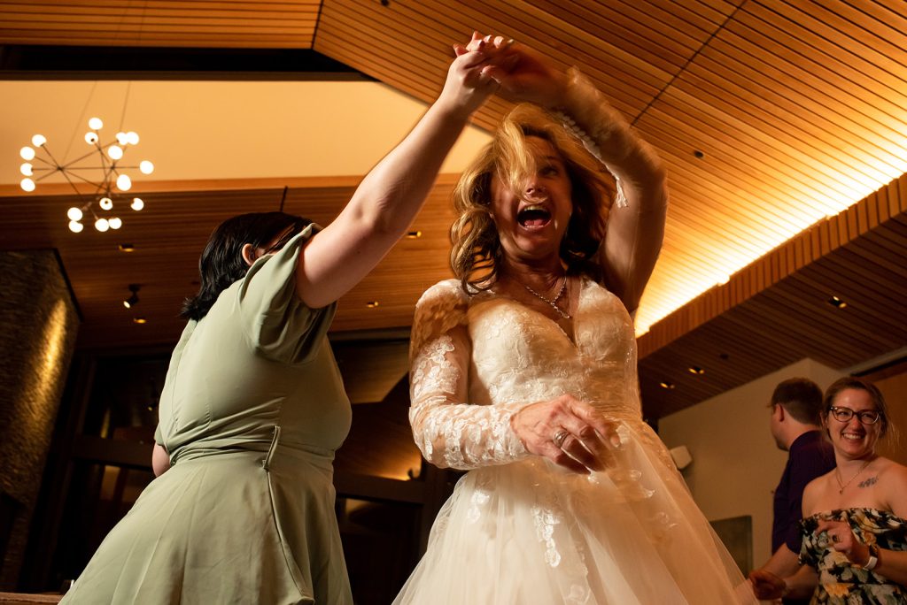a woman in a wedding dress dancing with another woman.